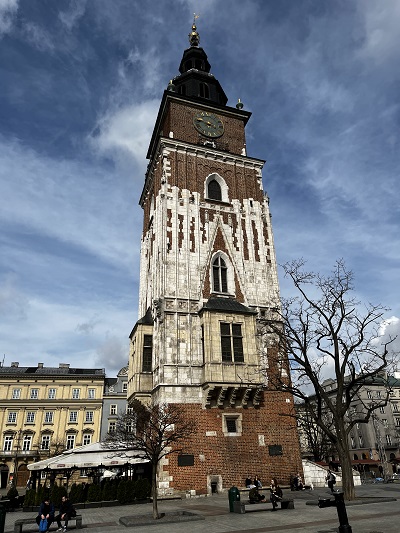 Wieża ratuszowa na Starym Rynku Krakowie na tle niebieskiego nieba z widocznym zegarem